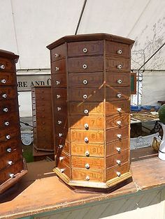 three wooden dressers sitting on top of a table next to each other in front of a tent