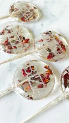 four lollipops with the word love on them sitting on a marble surface