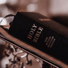 a black book sitting on top of a metal stand next to a glass candle holder