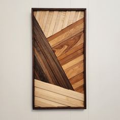 a wooden wall hanging on the side of a white wall with wood strips in it