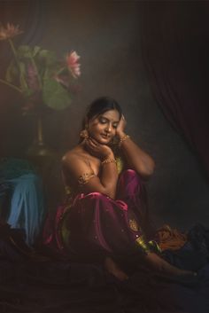 a woman sitting on top of a bed next to a flower