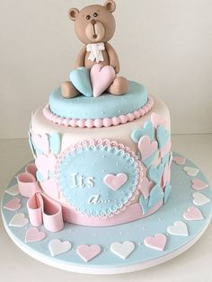 a teddy bear sitting on top of a blue and pink cake with hearts around it