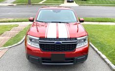 a red truck with white stripes parked on the street