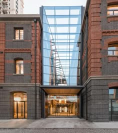 the entrance to an office building with brick walls and glass doors on both sides, surrounded by tall buildings