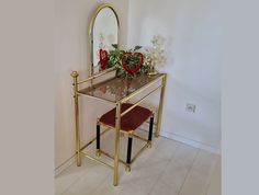 a vanity with a mirror, stool and flowers on the table in front of it