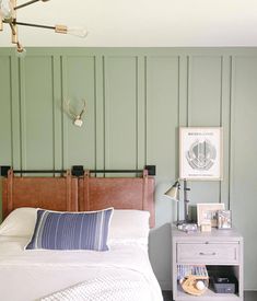 a bedroom with green painted walls and white bedding, along with a wooden headboard