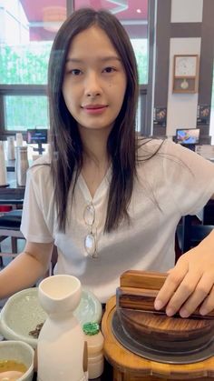 a woman sitting at a table with food in front of her and chopsticks