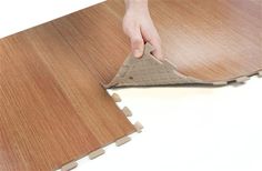 a person is placing the floor tiles on top of another piece of wooden planks