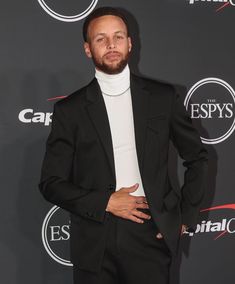 a man in a black suit and white turtle neck sweater at an espy's event