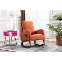 an orange rocking chair sitting on top of a rug next to a potted plant