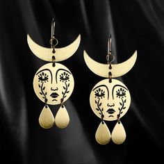 Horned Mother Moon earrings with etched faces comprised of weeping flowers and a waning crescent crown. For more companions of the Horned Mother Moon Earrings, check out our Classics collection. 2.4" in length x 1.2" in width nickel free brass pendants. Available with gold filled hooks. For a necklace version of the Horned Mother Moon design, check here. These have black enamel filled details. They are also powder coated to prevent the metal from oxidizing, preserve the enamel and makes the ... Gold Moon-shaped Earrings, Bronze Dangle Brass Earrings, Gold Moon-shaped Pierced Earrings, Gold Moon Shaped Pierced Earrings, Gold Copper Festival Earrings, Gold Colored Copper Earrings For Festivals, Gold Copper Earrings For Festival, Hypoallergenic Gold-tone Brass Jewelry, Teardrop Brass Plug Earrings