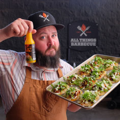 a man with a beard holding a tray of food and a bottle of orange juice