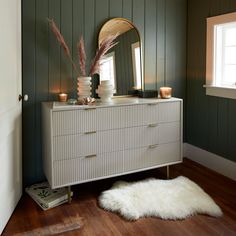 a white dresser sitting next to a window in a room with green walls and wooden floors