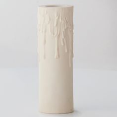 a white ceramic vase with dripping paint on the outside and inside, against a white background