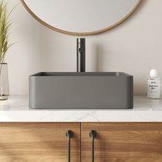 a bathroom sink sitting on top of a counter next to a wooden cabinet and mirror