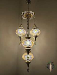 a chandelier hanging from the ceiling with three lights on each side and an ornamental design