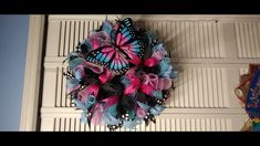 a blue and pink butterfly wreath hanging on the side of a door