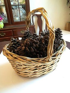 a basket filled with pine cones sitting on top of a white table next to a dresser