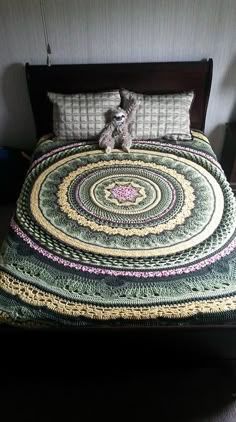 a bed with a quilted bedspread and two stuffed animals on top of it