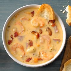 there is a bowl of soup with shrimp and bread on the table next to it