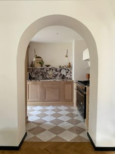 an archway leading into a kitchen with marble counter tops and wooden cabinets on either side