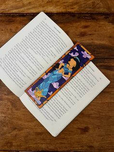 the bookmark is laying on top of an open book, which has been decorated with cartoon characters