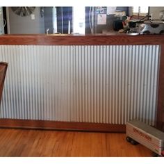 an empty room with a metal wall and wood flooring on the walls, in front of a mirror