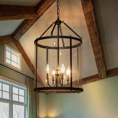 a chandelier hanging from the ceiling in a room with wood beams and windows