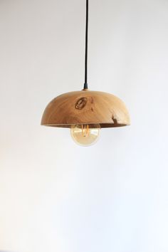 a wooden light fixture hanging from a ceiling with a white wall in the back ground