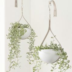 two hanging planters with plants in them and one holding a potted plant on the other side