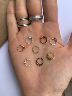 a person's hand holding seven rings in different shapes and sizes, all on top of each other