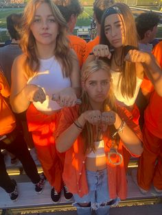 three girls in orange prison uniforms are holding their hands up and posing for the camera