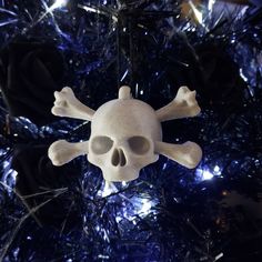 a skull and crossbone ornament hanging from a christmas tree with blue tinsel