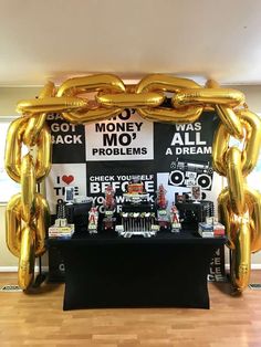 a table topped with gold balloons and lots of money on it's back wall