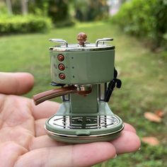 someone is holding a miniature coffee maker in their hand