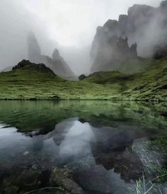 the mountains are covered in fog and mist as they sit on top of a lake