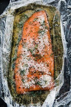 a piece of cooked salmon sitting on top of aluminum foil covered in parmesan cheese