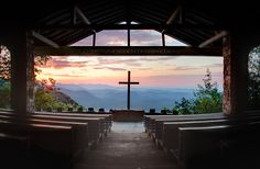 an empty church with the sun setting over mountains in the backgrounds