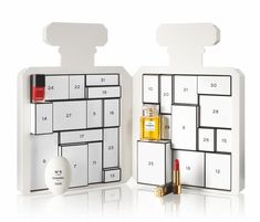 two white calendars with lipstick and perfume bottles on them, one is shaped like a cube