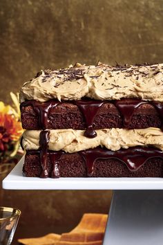 a cake with frosting and chocolate drizzles on it, sitting on a white platter