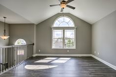 an empty room with a ceiling fan and windows