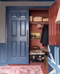 a blue door is open in a room with red walls and rugs on the floor