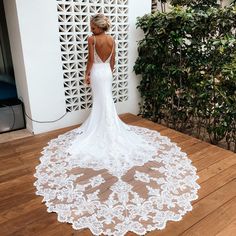 a woman in a white wedding dress standing on a wooden floor with her back to the camera