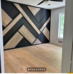 an empty room with wood flooring and black wallpaper on the walls, along with a ceiling fan