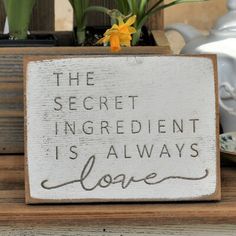 a wooden sign that says the secret ingredient is always love on top of a table