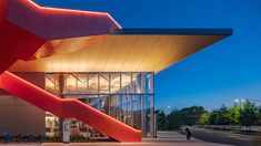 a building that has a red staircase on the outside and people walking in front of it