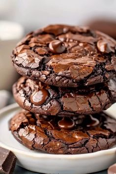 three chocolate cookies stacked on top of each other in front of some milk and chocolate chips