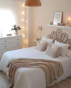 a bed with white sheets and pillows in a bedroom next to a window filled with lights