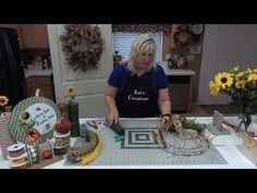 a woman standing in front of a table filled with assorted crafts and decor items