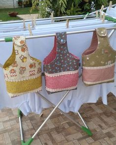 three aprons are hanging on a clothes line with white table cloth and green legs